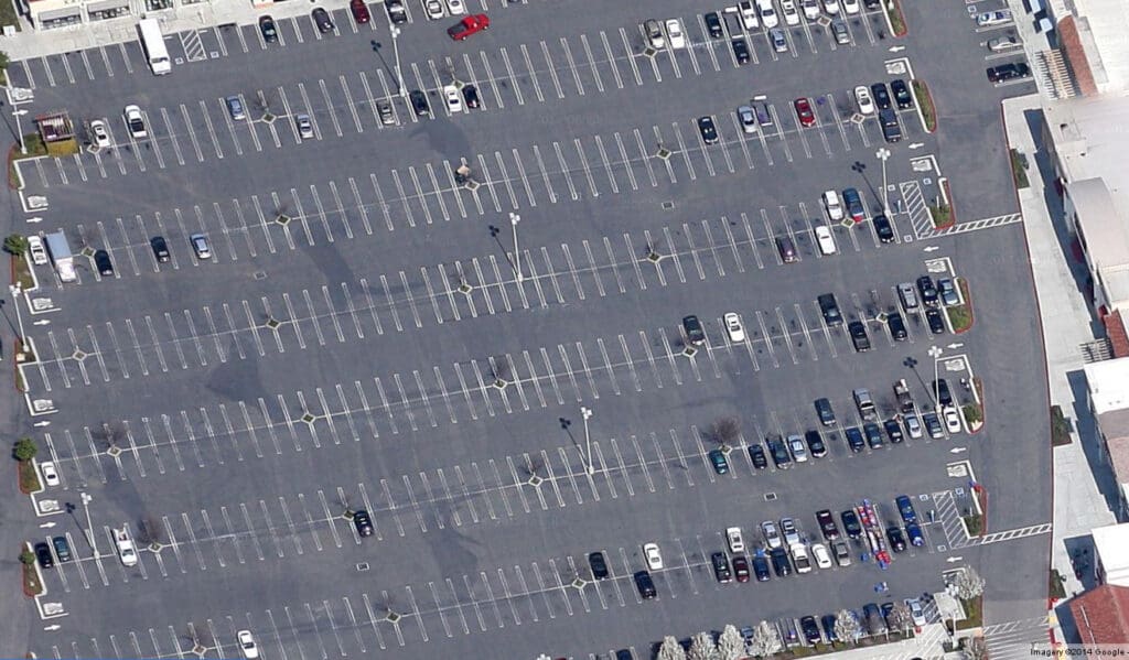Parking lot with hundreds of empty parking spaces. Cars only park along the edges.